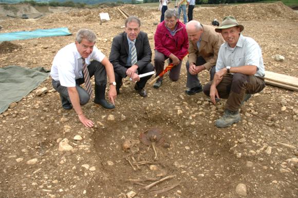 Landrat Frank Hämmerle, Bürgermeister Johannes Moser, Irene Völlinger, Wunibald Wikenhauser und Kreisarchäologe Dr. Jürgen Hald (von links) vor dem etwa 4300 Jahre alten Grab einer Frau, die mit einem Hals- oder Brustschmuck aus Knochenperlen sowie mehreren Tongefäßen der sogenannten Glockenbecherkultur am Ende der Jungsteinzeit bestattet wurde.