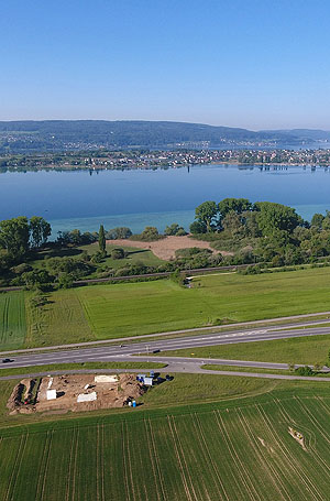 Blick vom Festland bei Allensbach auf die Insel Reichenau. Im Vordergrund ist die Ausgrabungsstätte des Richtplatzes zu sehen, auf welchem die auf der Insel Reichenau abgeurteilten Personen bis ins 18. Jahrhundert hingerichtet wurden.