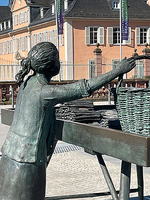 Bronzeskulptur der Spargelfrau, Detail: Das Mädchen Annemarie als Kundin.